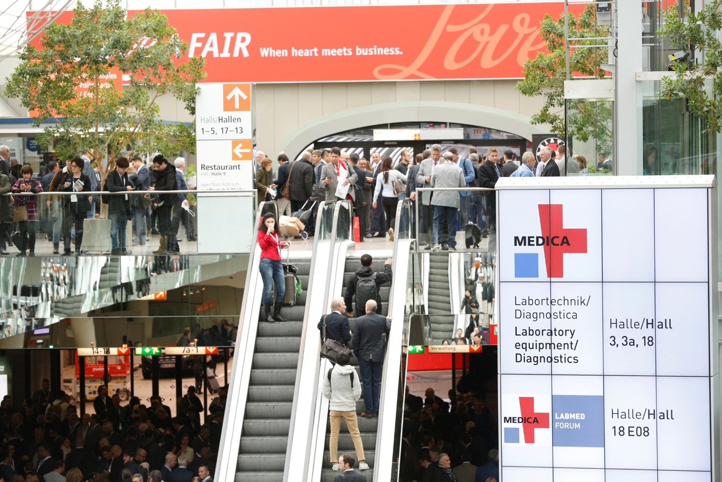 Na zdjęciu widać tłum ludzi czekających przed wejściem na teren targów medycznych oraz podążających do wejścia hali targowej 