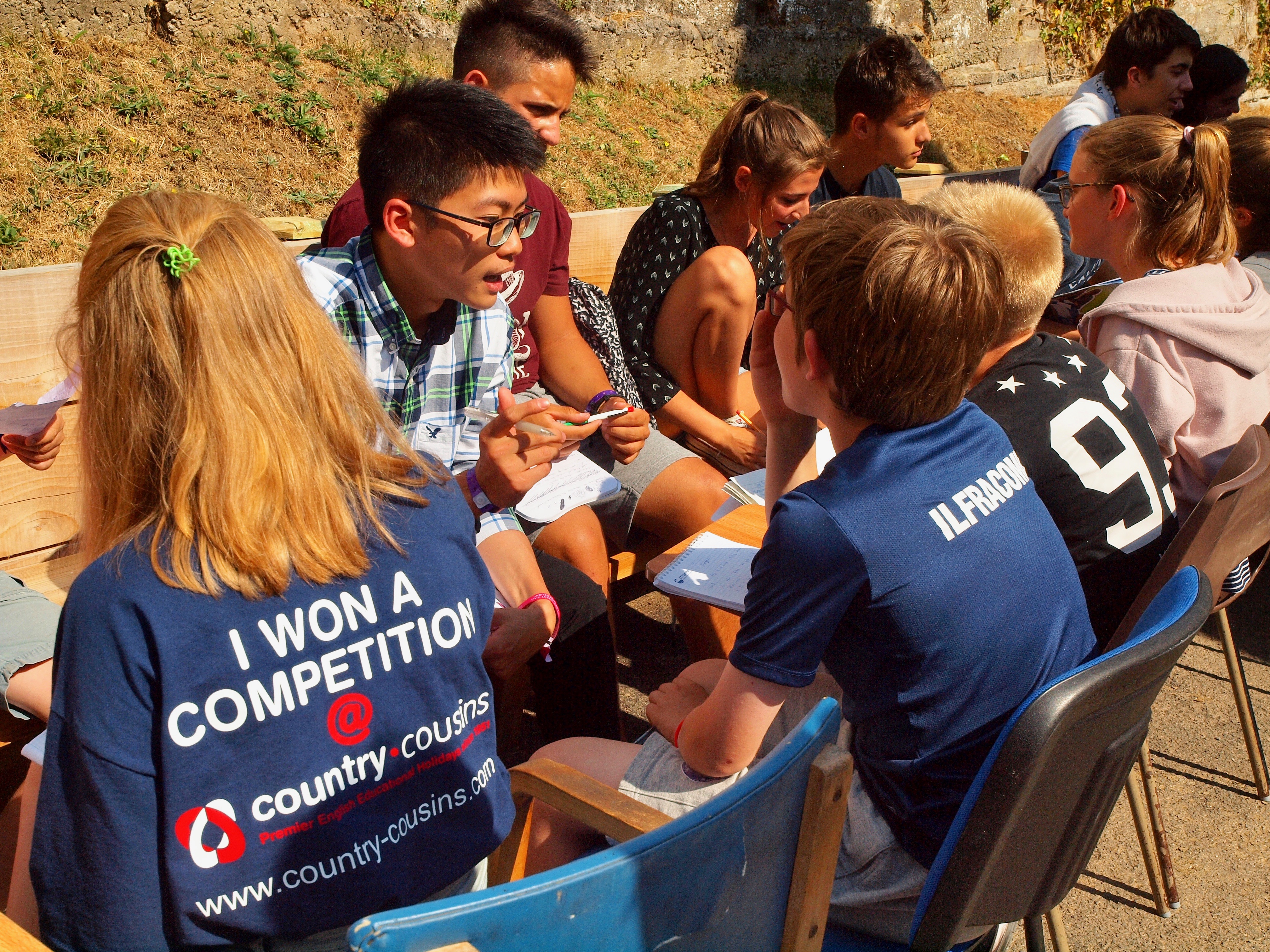 Grupa młodych ludzi różnych narodowości siedzących na krzesłach