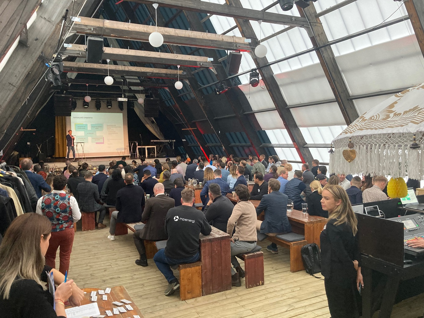 Sala ze sceną. Zgromadzenie ludzi przysłuchują się przemówieniu