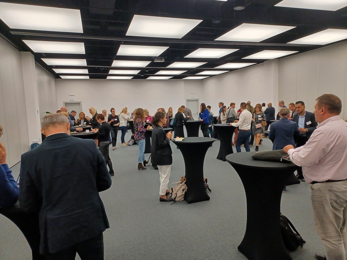 Ludzie stoją przy stolikach i rozmawiają