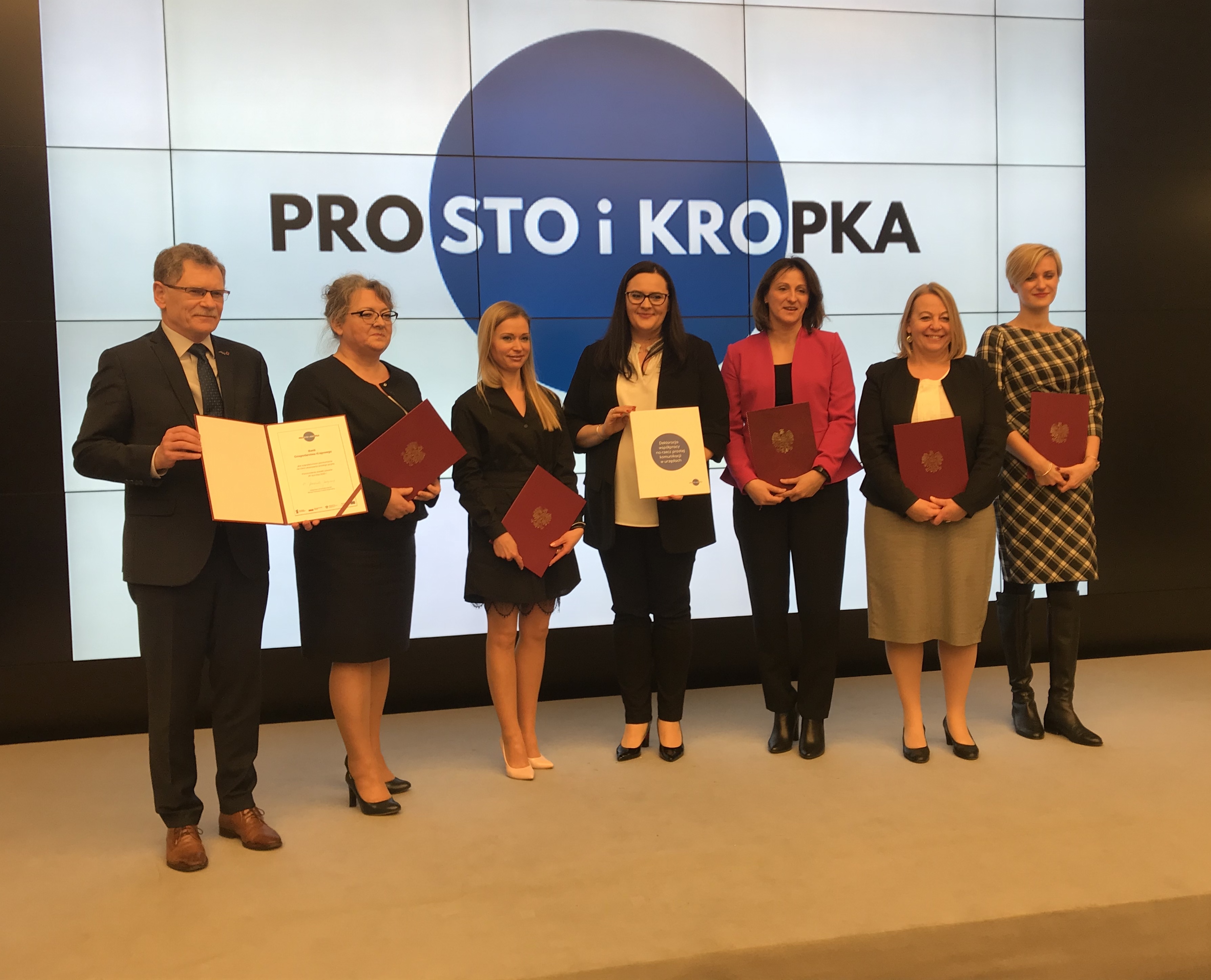 Sygnatariusze deklaracji współpracy na rzecz prostej komunikacji stojącyna scenie Sygnatariusze deklaracji współpracy na rzecz prostej komunikacji stojącyna scenie