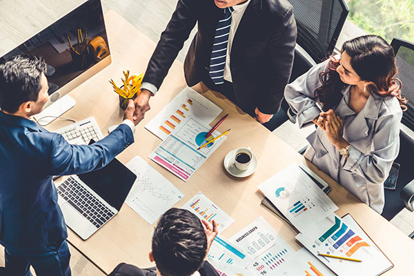 Widok z góry na grupę czterech osób siedzącą przy stole konferencyjnym i wymieniającą miedzy sobą...