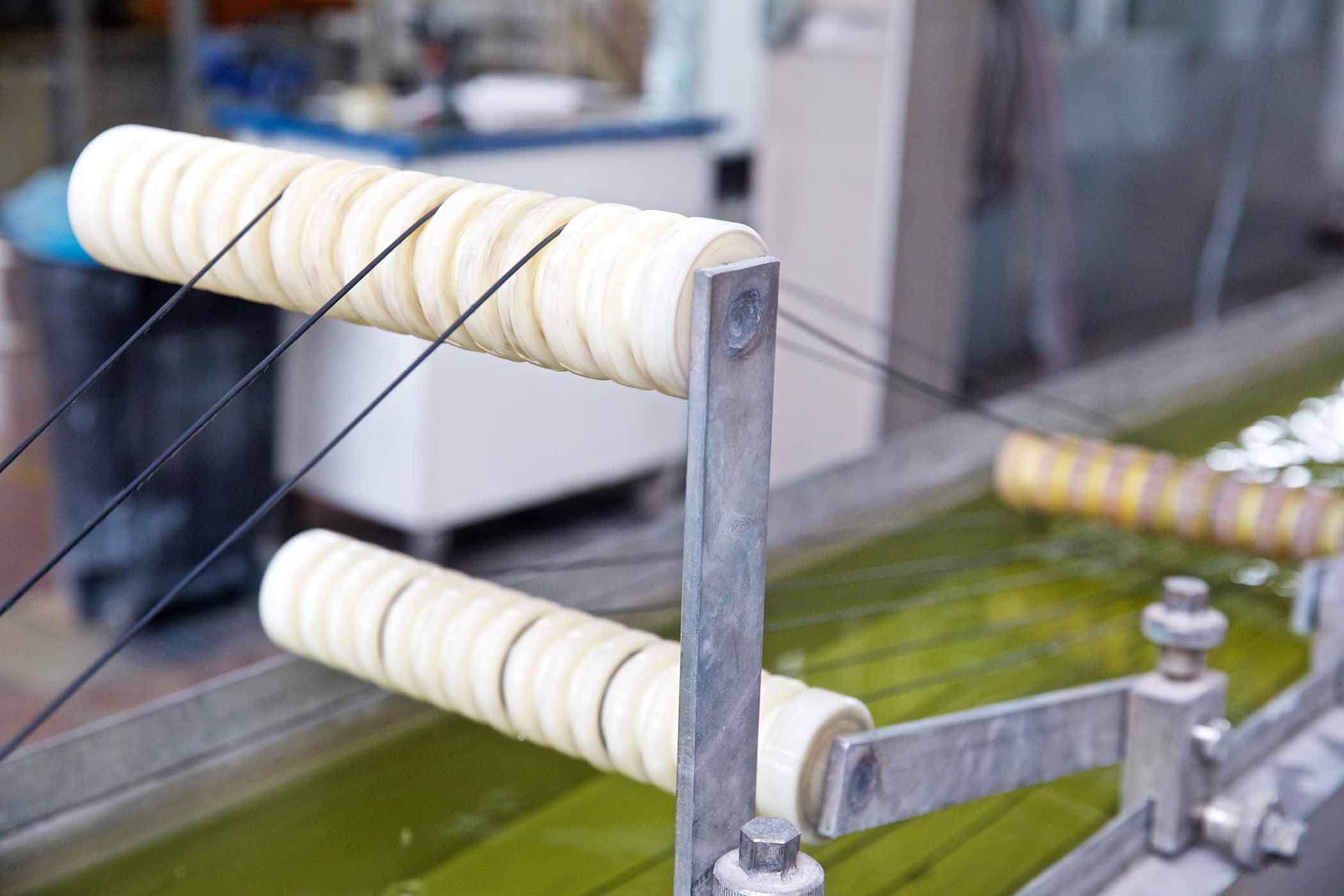 Zdjęcie hali z linią technologiczną w postaci taśmy z rolkami i płynem 