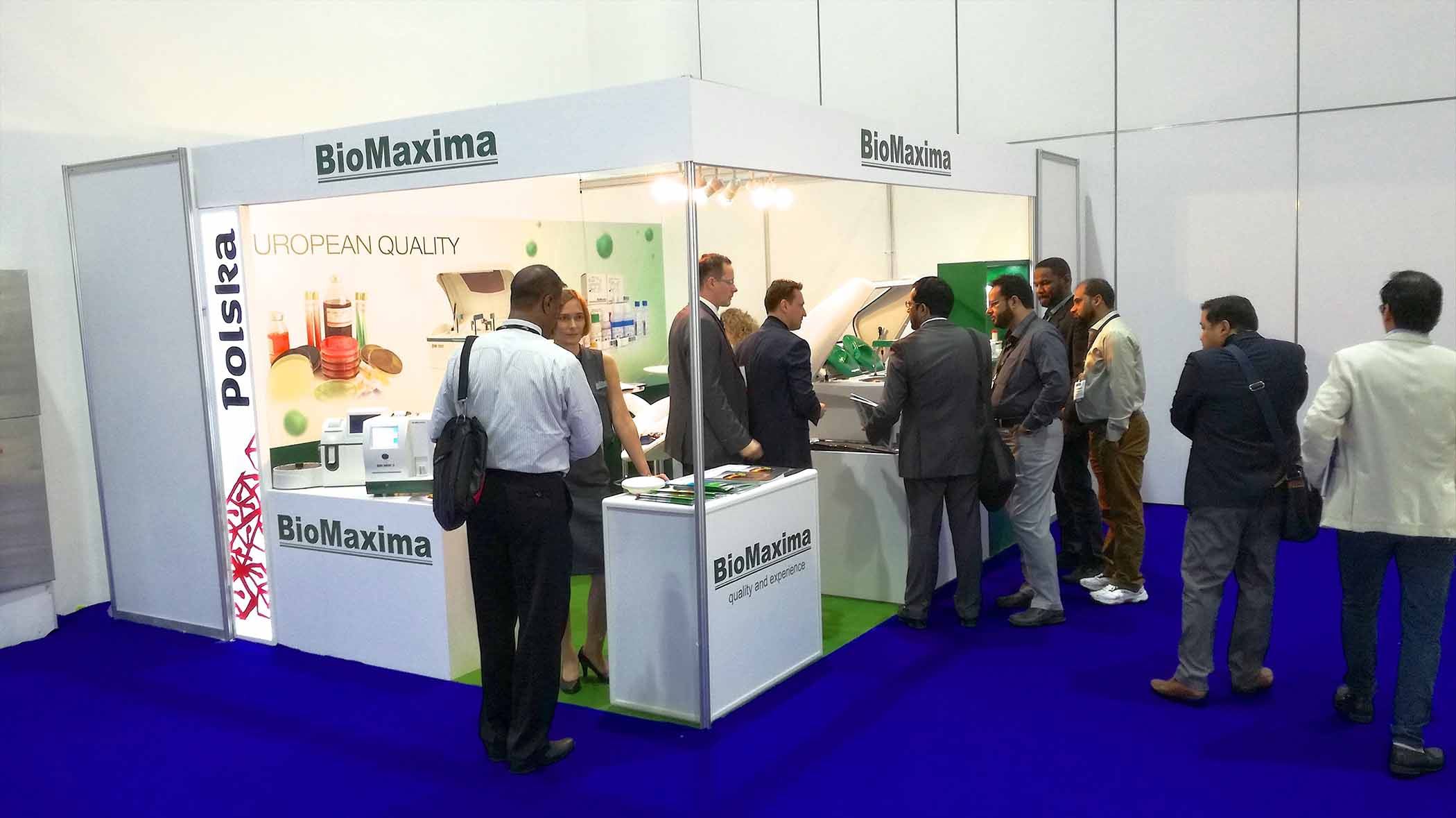 Zdjęcie soiska targowego z szyldem BioMaxima z stojącymi uczestnikami targów