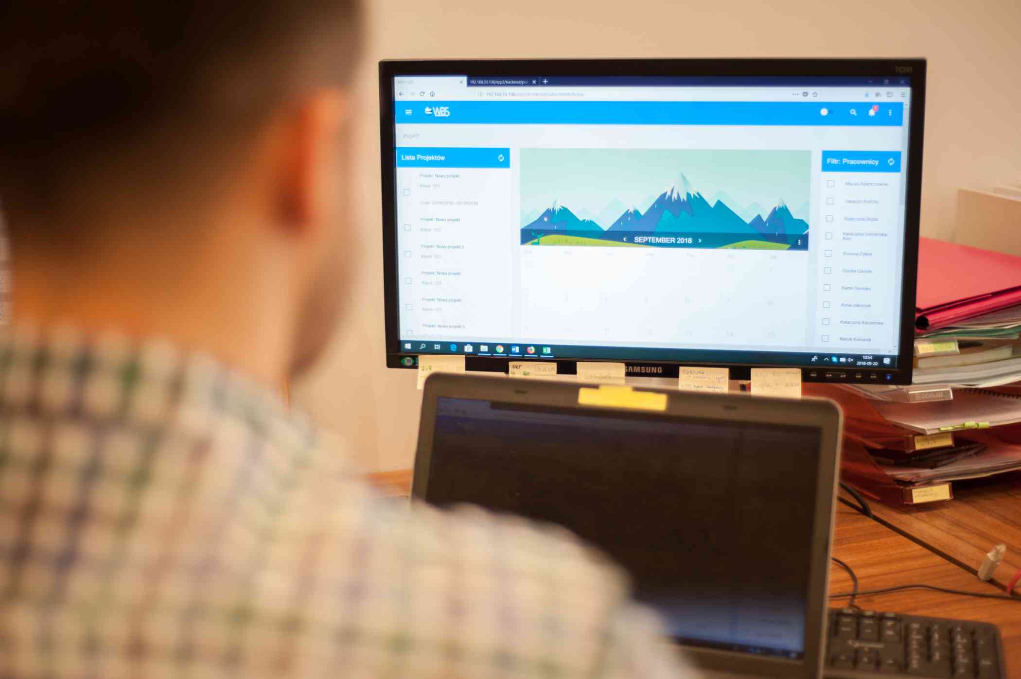 Komputer z wyświetloną na ekranie platformą w tle ręka człowieka