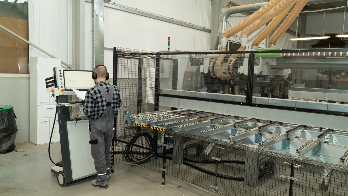 hala fabryczna przy maszynie pracownik odkręcony tyłem