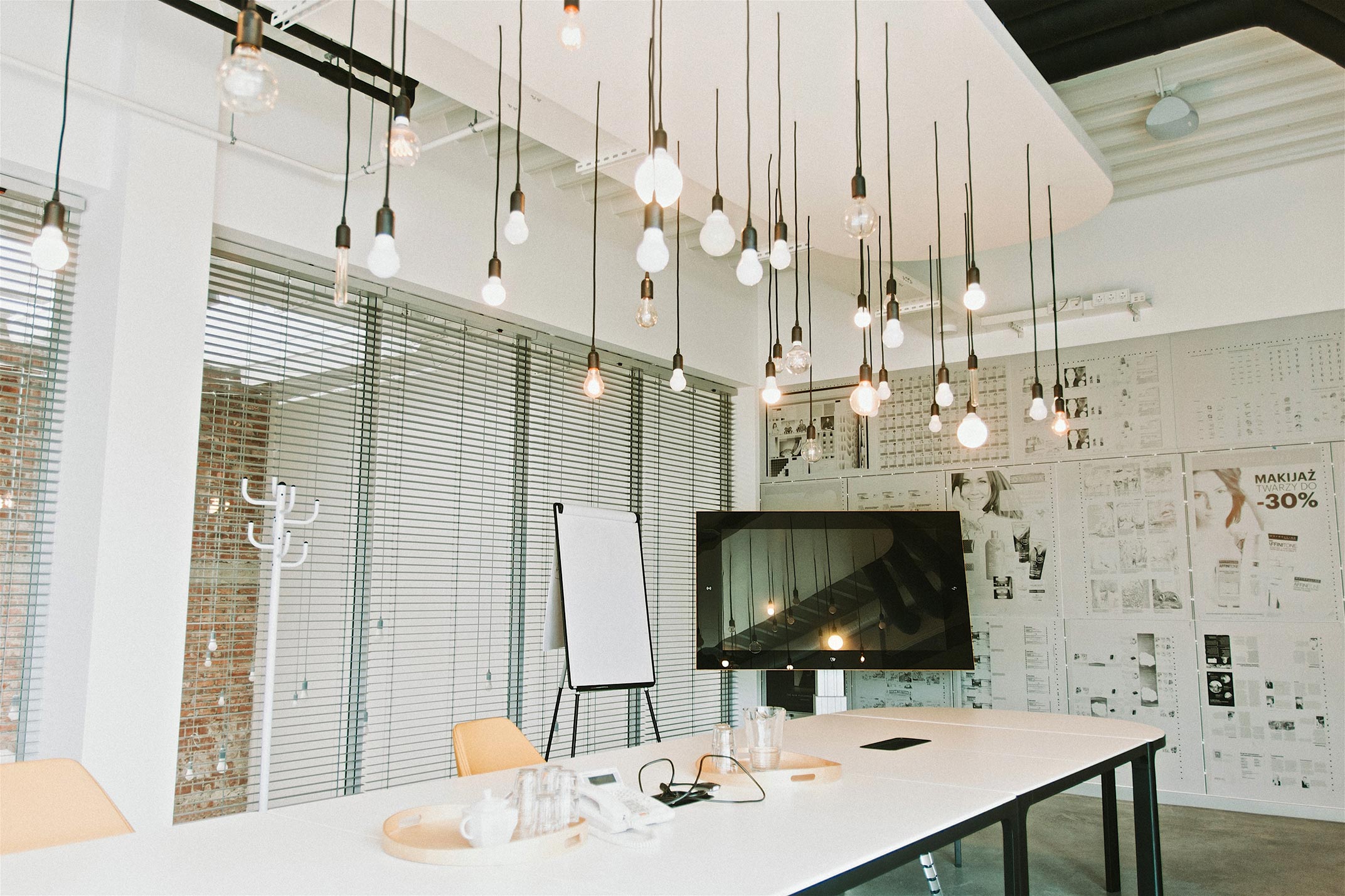 Widok wiszących żarówek nad stołem, na którym stoi komputer